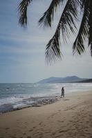 tropischer Strand während des sonnigen Tages mit der Silhouette der Frau foto