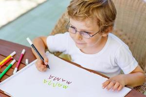 kleiner Junge mit Brille macht Hausaufgaben zu Hause
