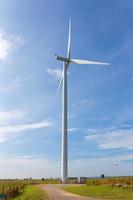 Ökostrom, Windkraftanlage auf dem grünen Gras und Maisfeld über dem blauen bewölkten Himmel foto