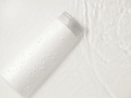 weiße flasche flakon kosmetik schönheitsprodukt zur hautpflege gesichtscreme und körperlotion duschgel natürliche organische kosmetik in wassertropfen rein schön. foto
