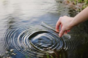 Wasserprobe. Hand sammelt Wasser, um es zu erkunden. Konzept - Wasserreinheitsanalyse, Umwelt, Ökologie. Wassertests auf Infektionen, Erlaubnis zum Schwimmen. selektiver Fokus, Platz für Text. foto