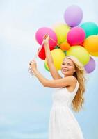 lächelnde Frau mit bunten Luftballons draußen