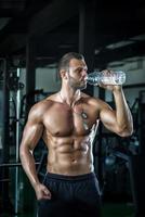 Mann Trinkwasser im Fitnessstudio foto