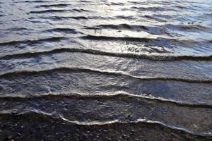 detaillierte nahaufnahme auf wasseroberflächen mit wellen und wellen und das sonnenlicht, das an der oberfläche reflektiert wird foto