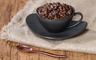 Kaffeebohnen in einer Kaffeetasse auf Sackleinen foto
