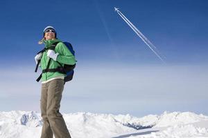 Flugzeug fliegt über Frau Rucksack auf schneebedeckten Berg foto