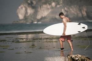 Surfer mit Surfbrett am Strand