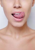 schöne Frau, die ihre Zunge herausstreckt und junges Piercing zeigt
