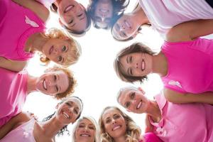 fröhliche Frauen im Kreis, die Rosa für Brustkrebs tragen
