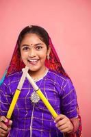 fröhliche indische attraktive schöne Teenager-Mädchen hält Dandiya-Sticks