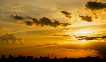 gibt ein warmes gefühl, sonnenuntergang hinter dem stadtgebäude, silhouette stadt hohe gebäude, gebäude silhouette wieder schöner himmel hintergrund und freiheitskonzept. foto