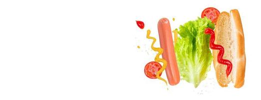 fliegende Zutaten für köstlichen Hotdog auf weißem Hintergrund. schwebende Wurst, Tomaten und Salat.