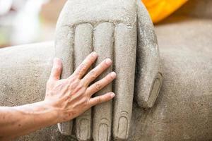 menschliche Hand und Hand der Buddha-Statue