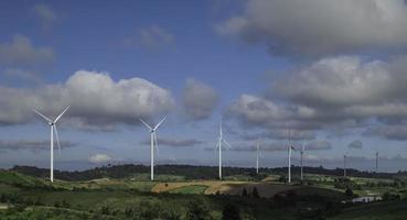 Ökostrom, Landschaft mit Hügeln und Windturbinenfeld auf blauem Himmelshintergrund. foto