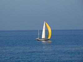 Sport-Segelboot-Segeln mit entfalteten Segeln auf blauem Meer foto