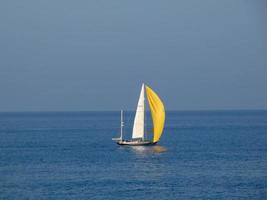 Sport-Segelboot-Segeln mit entfalteten Segeln auf blauem Meer foto