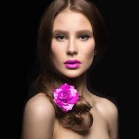 schönes Mädchen mit rosa Lippen und einer Rose foto