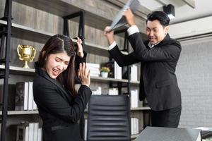 emotionale kollegen, die im büro kämpfen. Konflikte am Arbeitsplatz. wütender Chef. Mann als Chef im Büro geht gewalttätig gegen eine Frau als Angestellte vor foto