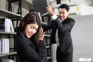 emotionale kollegen, die im büro kämpfen. Konflikte am Arbeitsplatz. wütender Chef. Mann als Chef im Büro geht gewalttätig gegen eine Frau als Angestellte vor foto