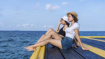 Zwei Freundinnen oder Paare entspannen sich und beobachten gemeinsam die Aussicht auf tropische Strandreisen in den Sommerferien. Touristinnen reisen in ihrer Freizeit gerne in die exotische Natur. Freundschaftskonzept foto