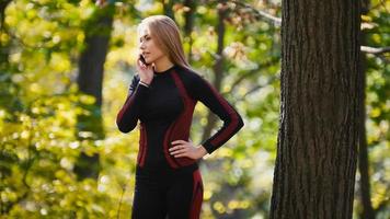 Junge, sportliche Frau, die am Handy im Herbstpark im Freien spricht, Nahaufnahme foto