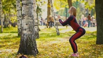 sexy attraktives weibliches blondes Bikini-Fitnessmodel, das sich im Herbstpark auf bodenbedeckten gelben Blättern ausdehnt - Sportkniebeugen foto