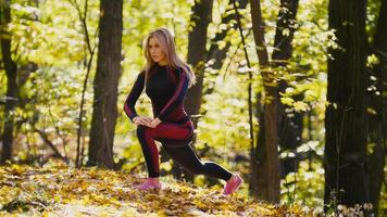 Frau macht Fitnessübungen im Freien. Weibchen, das sich im herbstlichen Wald ausdehnt. schlankes Mädchen beim Training foto