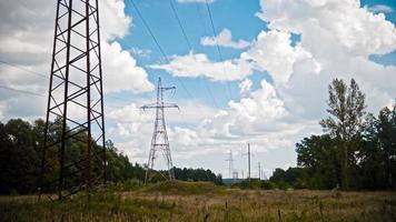 Breitbild-Zeitraffer von Stromleitungen und Hochspannungsmasten auf einem Feld auf dem Land im Sommer. foto