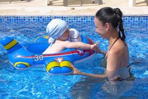 junge mutter, ein schönes mädchen und ein kind in einem aufblasbaren kinderkreis, in einem blauen pool im urlaub. foto