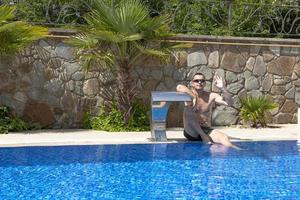 Sonnenbaden. Ein junger und gutaussehender Mann sonnt sich auf einer Sonnenliege im Pool. foto