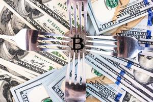 Platin-Bitcoin auf dem Hintergrund von Hundert-Dollar-Scheinen und Besteck. foto