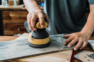 tischler verwenden exzenterschleifer oder palmschleifer poliert holz in der werkstatt, diy maker und holzbearbeitungskonzept. selektiver Fokus foto