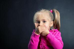 kleines Mädchen bedeckt ihren Mund mit den Händen