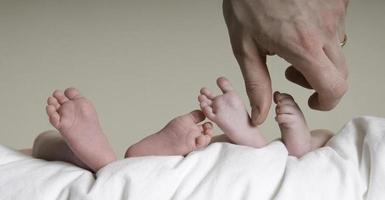Baby Zwillingsfüße mit der Hand des Vaters