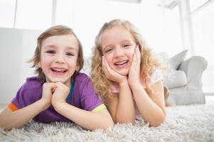 glückliche Geschwister, die zu Hause auf Teppich liegen foto