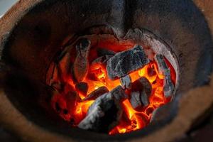 orange Flamme der Holzkohle im Grill aus uraltem Ton. Weicher Fokus. foto