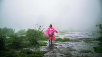 Tourist mit rosa Regenmantelstand Blick auf die Landschaft natürlicher schöner Berührungsnebel im Nationalpark Phu Hin Rong Kla. reise natur, reise entspanne, reise thailand, regenzeit. foto