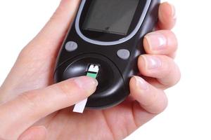 Nahaufnahme von Glukosemessgerät und Finger auf weißem Hintergrund