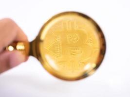 goldene bitcoin-lupe auf einem verschwommenen hintergrund von münzen foto