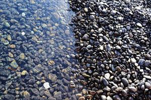 bunte kieselsteine, die welle berühren foto