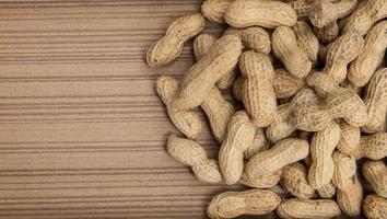 Erdnüsse in Schalen über Holz Hintergrund foto