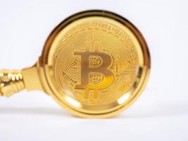 goldene bitcoin-lupe auf einem verschwommenen hintergrund von münzen foto