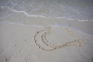 Herzen auf den Sand eines Strandes gezeichnet foto