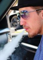 Mann im Fahrzeug bläst Dampf aus dem Mund foto