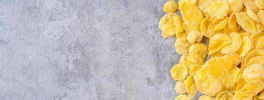 cornflakes-schüsselbonbons auf grauem zementhintergrund, flaches lagplandesign der draufsicht, frisches und gesundes frühstückskonzept. foto