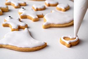 Nahaufnahme von niedlichen Halloween-Plätzchen mit Zuckerguss in Spritzbeutel dekorieren. foto