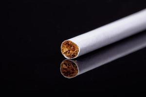 einzelne dünne Zigarette lokalisiert auf schwarzem Hintergrundmakro foto