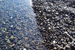 bunte kieselsteine, die welle berühren foto