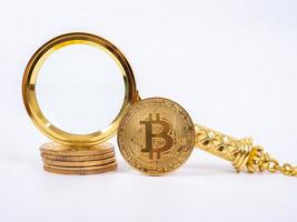 goldene bitcoin-replik und lupe auf weißem hintergrund. geschäfts- und finanzkonzept. foto