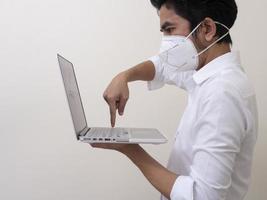 geschäftsmann in medizinischer gesichtsmaske arbeitet zu hause am laptop foto
